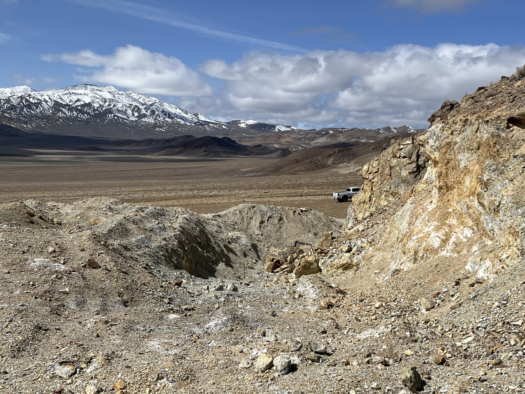 Open turquoise mine site with snow-covered Nevada mountains in the distance