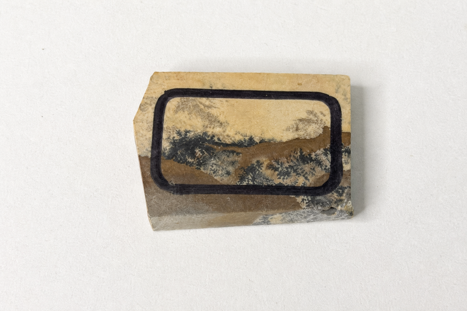 An isolated dendritic picture-stone slab with the intended cutting frame marked on its surface